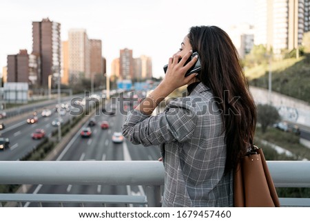 Stock photo of side view of a young business woman having a conversation on the phone. She is unrecognizable.