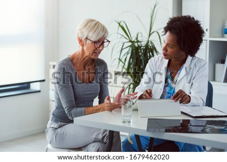 A female doctor sits at her desk and chats to an elderly female patient while looking at her  test results Royalty-Free Stock Photo #1679462020