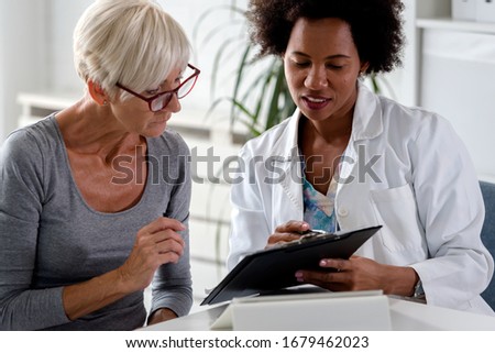 A female doctor sits at her desk and chats to an elderly female patient while looking at her  test results Royalty-Free Stock Photo #1679462023