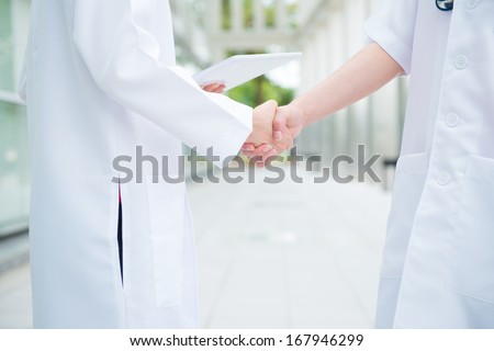 Two medical doctors shaking hands at hospital corridor, teamwork concept. Royalty-Free Stock Photo #167946299