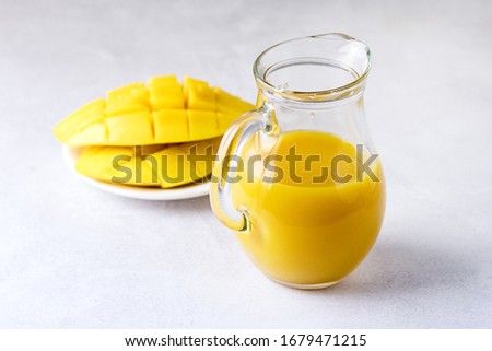 Glass Decanter of Tasty Ripe Mango Juice and Ripe Sliced Mango on Light Gray Background Vitamin and Healthy Drink Horizontal