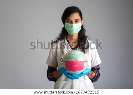 Woman doctor holding world globe with a medicine face mask. World epidemic of coronavirus concept.