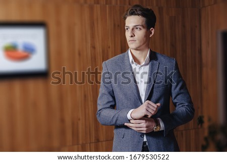 stylish guy in jacket at modern office on simple wooden background