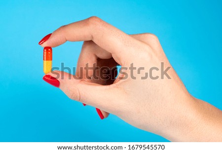 
pill in a female hand on a blue background