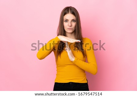 Young caucasian woman isolated on pink background making time out gesture
