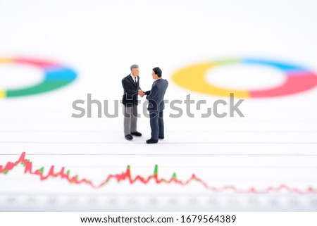 Miniature people:Businessman standing and shake hand with team with copy space. Financial crisis. Data analysis. Stock market volatility risk. Information for investment.