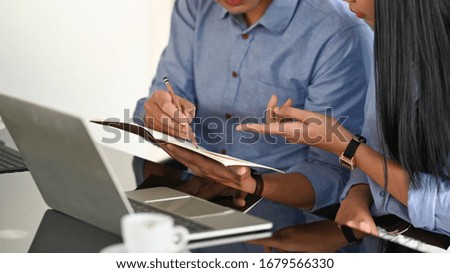 Cropped image of business developer team discussing/talking/working together with computer tablet, laptop and document while sitting at the modern working desk over comfortable office as background.