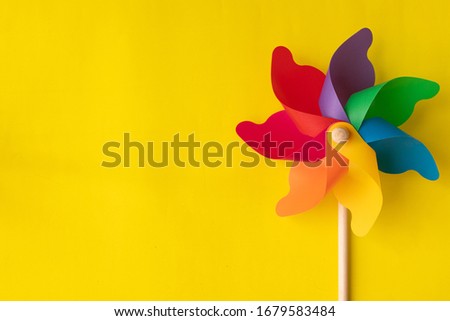 Flat lay Rainbow pinwheel on yellow background, copy space. Royalty-Free Stock Photo #1679583484