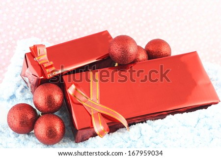 Red Christmas gift box with its lid propped at an angle in front to display the beautiful shiny metallic gold ribbon with falling winter snowflakes and copyspace for your greeting or wishes 
