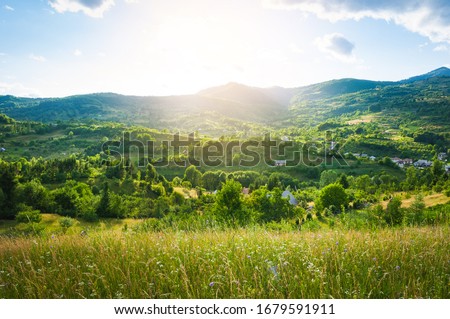 A peaceful landscape, green hills in spring time. A country road is cutting through the immaculate grass, illustrating the idea of travel , tourism or exploring Royalty-Free Stock Photo #1679591911