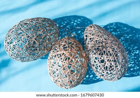Decorative creative  Easter eggs made of thread on a blue background with bright shadows from sunlight, light holiday of the Resurrection