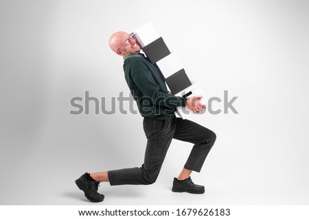 Beautiful caucasian male with glasses in black wear holds and carries different black and white boxes isolated on white background