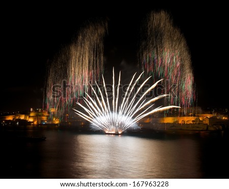 Colorful amazing fireworks in Valletta, Malta with city and reflection background, city silhouette, Malta fireworks festival,4 July,Independence day,explode, dark sky background and house light. Malta