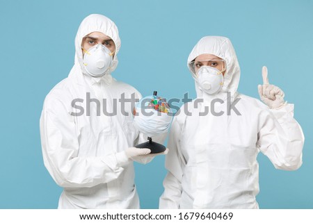 People in protective suits respirator masks hold globe isolated on blue background studio. Epidemic pandemic new rapidly spreading coronavirus 2019-ncov from Wuhan China, medicine flu virus concept