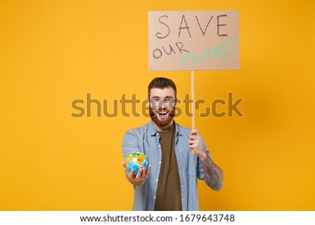 Excited young protesting man hold protest sign broadsheet placard on stick, Earth world globe isolated on yellow background. Stop nature garbage ecology environment protection concept. Save planet