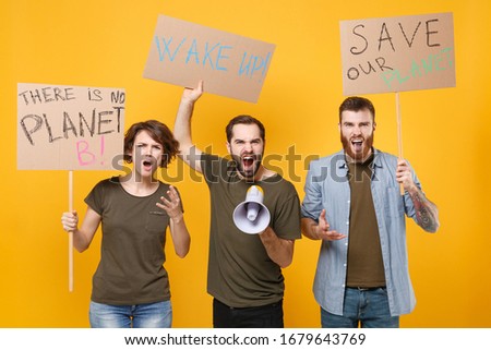 Angry protesting young three people hold protest signs broadsheet placard scream in megaphone isolated on yellow background. Stop nature garbage ecology environment protection concept. Save planet