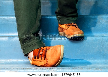 Close up portrait of legs with sneakers walking down stairs and spraining or dislocating ankle. Royalty-Free Stock Photo #1679645155