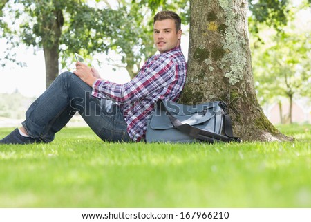 Smiling student using his tablet to study outside on college campus