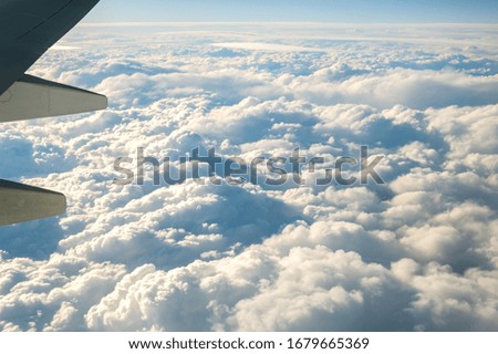 View from airplane on the aircraft white wing flying over cloudy landscape in sunny morning. Air travel and transportation concept.