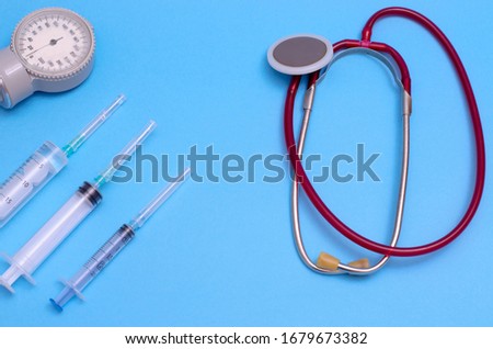 The fight against coronavirus. Vaccinations against covid 19. Medical stethoscope, syringes and tonometer on a blue background. Medical instruments. Place for your text. Medical background
