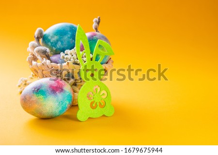 Easter concept with rabbit and eggs in basket on a yellow background. copyspace for text