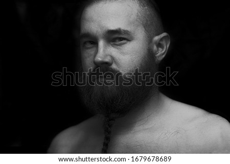 A Viking man with a braided beard on a black background. Monochrome black-and-white photo. 