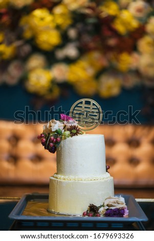 Close up of a double layer wedding cakes with flower decoration and double happiness plastic board