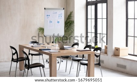 Empty modern loft office space with wooden table, electronic appliances notebooks ready for meeting, working workplace with no people prepared for briefing, whiteboard presentation or training Royalty-Free Stock Photo #1679695051