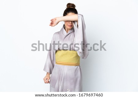Woman wearing kimono over isolated background covering eyes by hands
