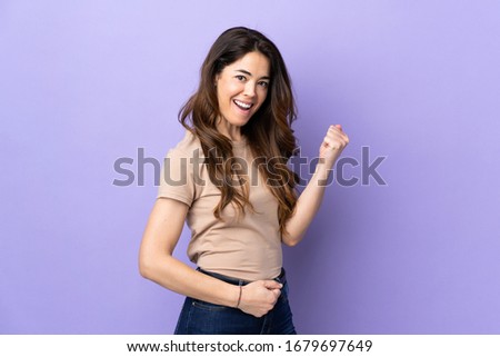 Woman over isolated purple background celebrating a victory