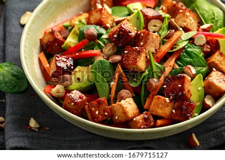Healthy Vegan Fried Tofu salad with carrot, red bell pepper, spinach and nuts