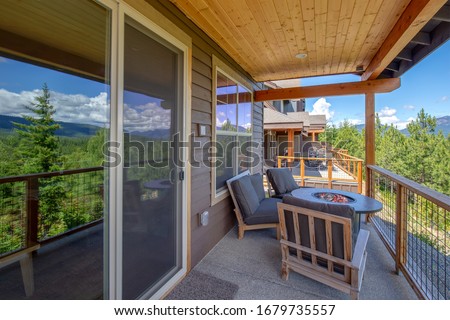 Amazing balcony patio with fire pit and forest and mountains view. Dream come true home exterior. New American architecture. Comfortable and beautiful home details.
