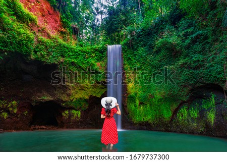 Asian woman at amazing Tibumana Waterfall Bali - the best cascade in Indonesia