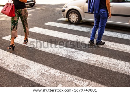 Rome Italy. Some people cross an asphalted road, passing on the pedestrian crossings. Framing on the legs and feet.