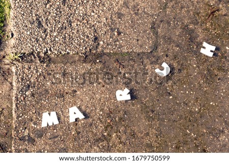 The word MARCH in paper letters on a background of gray stone.