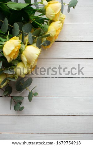 bouquet of yellow roses with eucalyptus branches on white boards