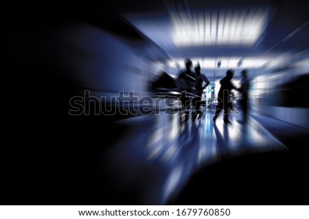 Silhouetted picture of man staff nurse assistant taking a patient lying on nursing bed to the doctor in a hurry with dark copy space. Background process with zoom out effect for COVID-19 concept. Royalty-Free Stock Photo #1679760850