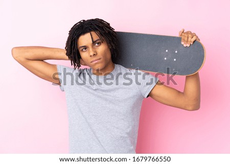 Young African American skater man over isolated pink wall