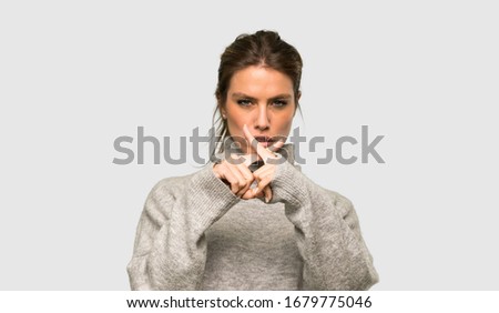 Blonde woman with turtleneck showing a sign of silence gesture over isolated grey background