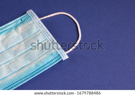 Medical protective three-layer disposable blue mask on a blue background. Protection against viruses and diseases.