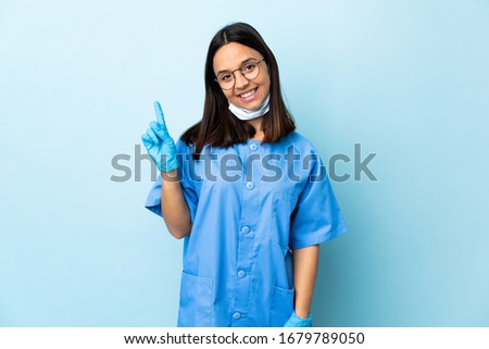 Surgeon woman over isolated blue background showing and lifting a finger in sign of the best