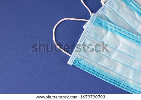 Medical protective three-layer disposable blue masks on a blue background. Protection against viruses and diseases. Close-up.