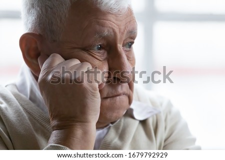 Old man feeling disappointed, lost in sad thoughts close up portrait. Baby boomer generation 80s grandfather suffers from loneliness, chronic or dementia senile diseases, life troubles regrets concept Royalty-Free Stock Photo #1679792929