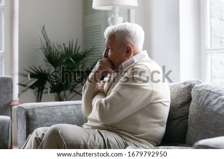 Grey haired old man sit on couch in living room alone, lost in sad pessimistic thoughts related to senile disease, mental disorder memory loss or dementia. Life troubles and lonely 80s person concept Royalty-Free Stock Photo #1679792950