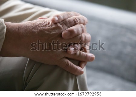 Old man sitting on couch close up view palms folded on knee. Concept of older generation lonely person, senile diseases osteoarthritis rheumatoid arthritis, male during psychological therapy session Royalty-Free Stock Photo #1679792953