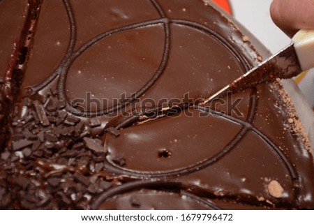 Hand with a knife cuts a chocolate cake closeup. Tasty holiday treat