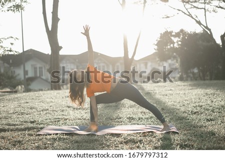 Portrait of young woman practicing yoga exercise during morning sunrise in the park. Calmness and relax, female happiness. Health lifestyle concept.
