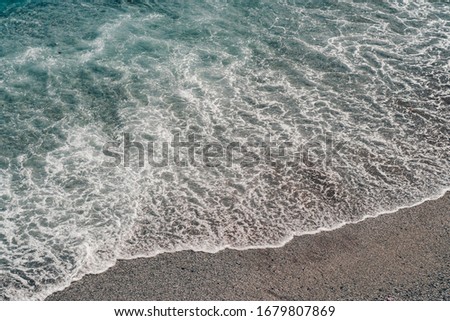 Top view of a deserted beach. The Italian coast of the Ligurian Sea. Aerial photo of seawaves reaching shore