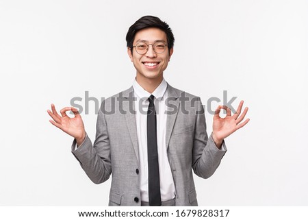 Keep calm and stay healthy. Handsome cheerful smiling asian male entrepreneur, office worker staying calm, holding hands in zen gesture, relaxing, meditating, white background