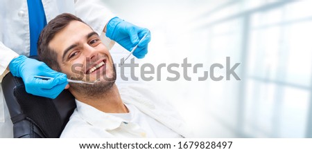 young man in the dental clinic with tools and hands of the dentist